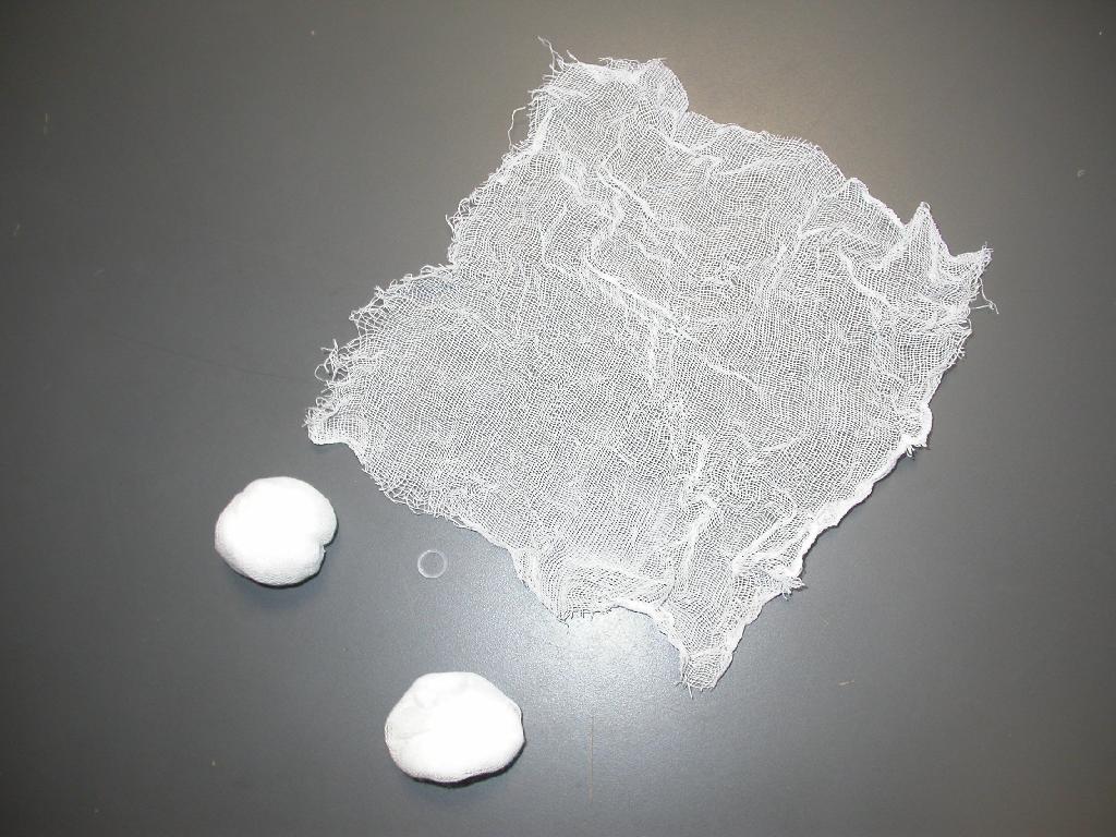 Nesterilni izdelek v obliki tampona (kroglice) povezanega s pomočjo silikonske elastike. Izdelan je iz gaze, tkane v platno vezavi iz enojne bombažne preje, kvadratne oblike, velikosti 20 x 20 cm, ki ima nezarobljene robove. Uporablja se za medicinske namene.
Pakirano po 100 kosov, za prodajo končnemu potrošniku, brez predhodnega prepakiranja (prodaja na drobno) in opremljeno z etiketo.