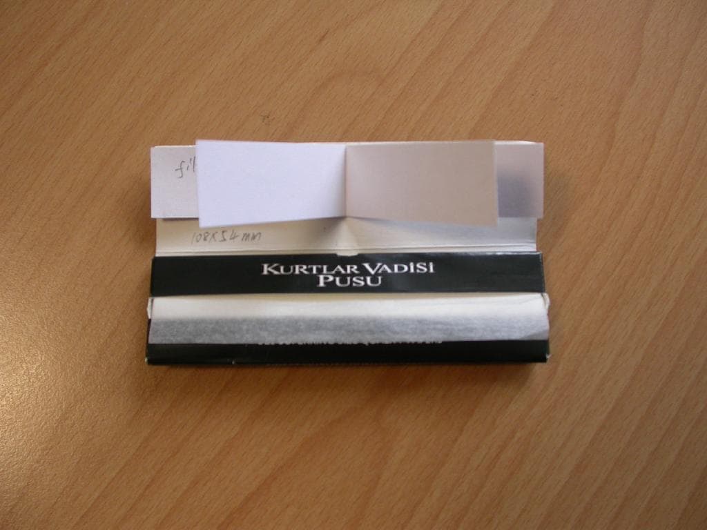 Cigaretni papir narejen iz riževe mase, gramature 14 g/m2, v obliki prosojnih lističev velikosti 10,8 x 5,4 cm, ki so po dolžini, na enem robu enostransko premazani s tankim slojem lepila. 
Lističi so vloženi v kartonast ovitek, na katerem so nalepljeni kosi narezanega surovega belega papirja, gramature 180 g/m2, ki so namenjeni oblikovanju cigaretnih filtrov za zvijanje tobaka. 

Cigaretni papir je namenjen zvijanju tobaka.

Pakirano po 32 lističev v kartonast ovitek.