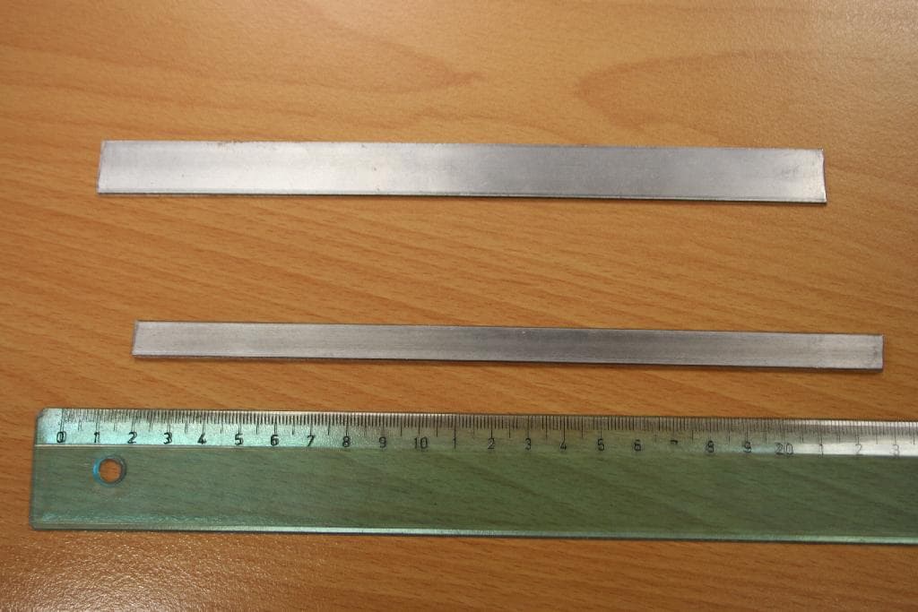 Neprekrit ali neprevlečen trak iz navadnih kovin – nelegiranega jekla s pravokotnim polnim prečnim prerezom, debeline 2,0 in širine 15,8 ali debeline 2,8 ter širine 9,9 mm. Sestava jekla : železo, 0,04 - 0,05 % ogljika, 0,30 - 0,32 % mangana, 0,04 - 0,11 % silicija, 0,008 - 0,009 % fosforja, 0,008 - 0,0130 % žvepla, 0,03 % kroma, 0,02 - 0,05 % niklja, do 0,01% molibdena in 0,03 - 0,09 % bakra. . Izdelek se transportira v obliki kolobarjev v tesno navitih slojih. Trak je izdelan s hladnim valjanjem iz jeklene žice.

Uporablja se za izdelavo stavbnega okovja.