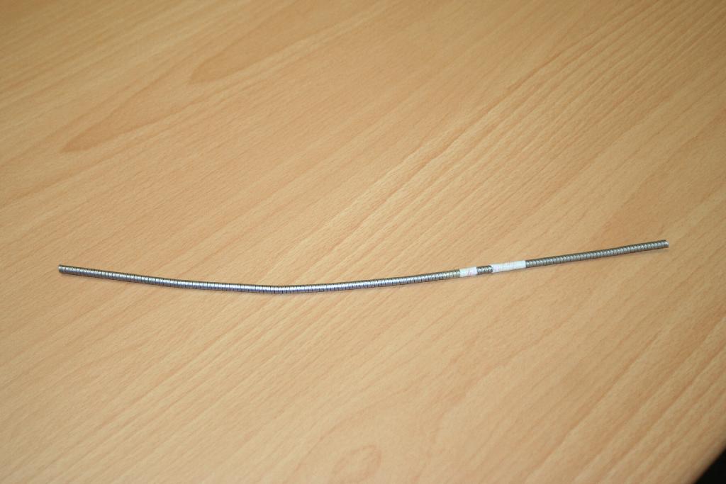 Izdelek v obliki hladno vlečene žice iz navadnih kovin premera Ø 1,20 mm, ki je spiralno ovita okrog cevi iz plastičnih mas.
Uporablja se za izdelovanje 'bovden' potegov.
Žica je izdelana iz nelegiranega jekla (sestava ogljik 0,70, mangan 0,63, silicij 0,22, fosfor 0,009, žveplo 0,015, krom 0,020, nikelj 0,010, baker 0,030, aluminij  0,002, molibden 0,001 % mas.%),
cev je izdelana ekstrudiranega politetrafluoroetilena (PTFE).
Žica je pakirana v metraži.
Bistven značaj izdelka predstavlja kovinska žica.