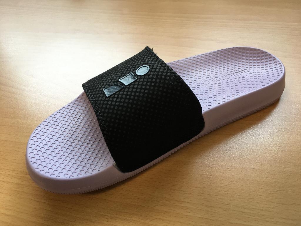 Obutev za prosti čas – natikači, s skupno višino podplata in pete manj kot 3 cm.
Natikači imajo podplat iz plastične (EVA-etilenvinilacetat) mase, lila barve in zgornji del – prednjik iz plastičnega (PU-poliuretan) paščka, črne barve, ki poteka čez nart stopala. Pašček je na spodnji strani podložen s sintetično pletenino in v sredini oblazinjen z mehko, plastično peno.