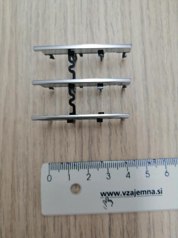 Tri redni vzporedni plastični okvirji pravokotne oblike dolžine 46 in širine 7 mm, z medsebojno razdaljo 16 mm.
Uporablja se kot okvir za sprednje plošče za avtoradie na armaturni plošči v avtomobilu.
Narejen je iz akrilonitril-butadien-stirena (ABS) in polikarbonata, prekrit s plastjo bakra (debeline 15 µm), niklja (7 µm) in kroma (0,3 µm). Debelina prevleke je manjša od 49 µm.