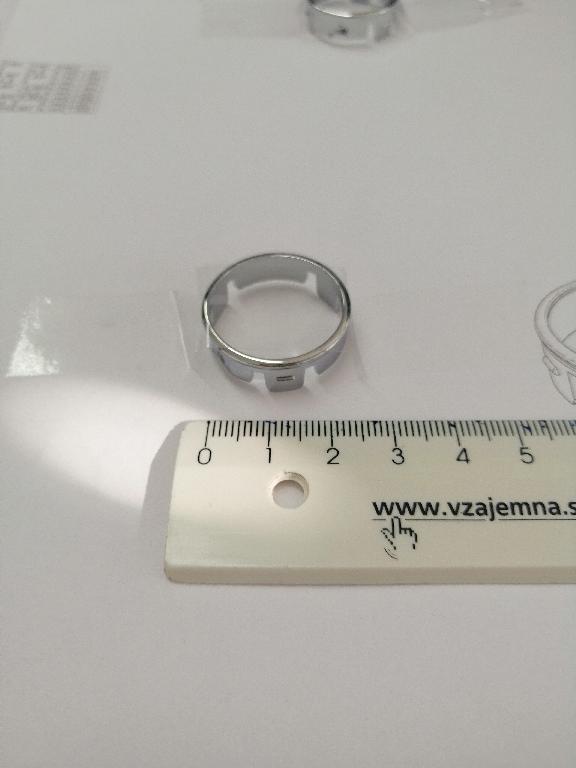 Plastični okvir okrogle oblike z zaobljenimi robovi. Okvir ima zunanji premer 25 in notranji premer 19 mm.
Uporablja se kot okvir za gumbe za avtoradie/klimatske naprave na armaturni plošči v avtomobilu.
Narejen je iz akrilonitril-butadien-stirena (ABS) in polikarbonata, prekrit s plastjo bakra (debeline 15 µm), niklja (7 µm) in kroma (0,3 µm). Debelina prevleke je manjša od 49 µm.