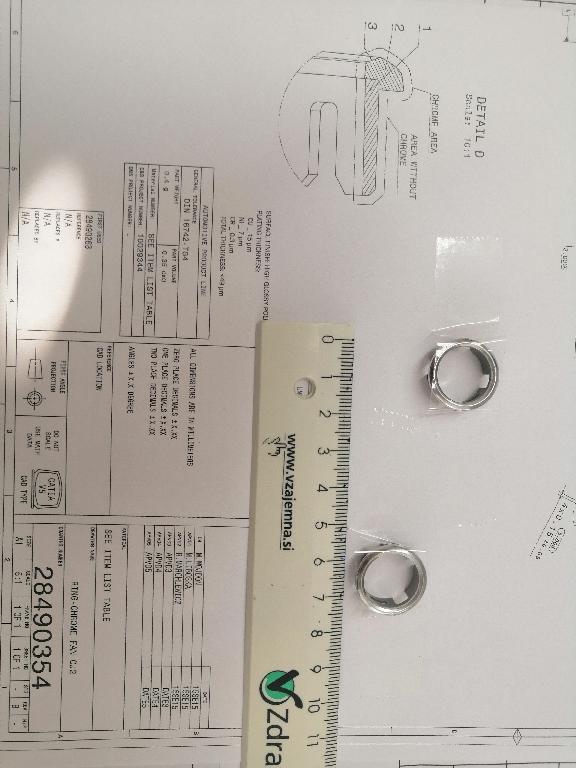 Plastični okvir okrogle oblike z zaobljenimi robovi. Okvir ima zunanji premer 19 in notranji premer 15 mm.
Uporablja se kot okvir za gumbe za avtoradie/klimatske naprave na armaturni plošči v avtomobilu.
Narejen je iz akrilonitril-butadien-stirena (ABS) in polikarbonata, prekrit s plastjo bakra (debeline 15 µm), niklja (7 µm) in kroma (0,3 µm). Debelina prevleke je manjša od 49 µm.