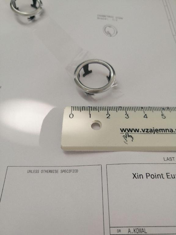 Plastični okvir okrogle oblike z zaobljenimi robovi. Okvir ima zunanji premer 25 in notranji premer 19 mm.
Uporablja se kot okvir za gumbe za avtoradie na armaturni plošči v avtomobilu.
Narejen je iz akrilonitril-butadien-stirena (ABS) in polikarbonata, prekrit s plastjo bakra (debeline 15 µm), niklja (7 µm) in kroma (0,3 µm). Debelina prevleke je manjša od 49 µm.