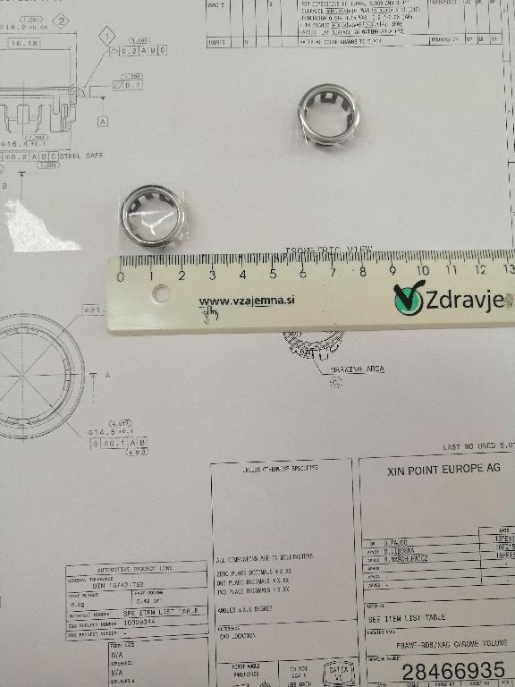 Plastični okvir okrogle oblike z zaobljenimi robovi. Okvir ima zunanji premer 21 in notranji premer 16 mm.
Uporablja se kot okvir za gumbe za avtoradie/klimatske naprave na armaturni plošči v avtomobilu.
Narejen je iz akrilonitril-butadien-stirena (ABS) in polikarbonata, prekrit s plastjo bakra (debeline 15 µm), niklja (7 µm) in kroma (0,3 µm). Debelina prevleke je manjša od 49 µm.
