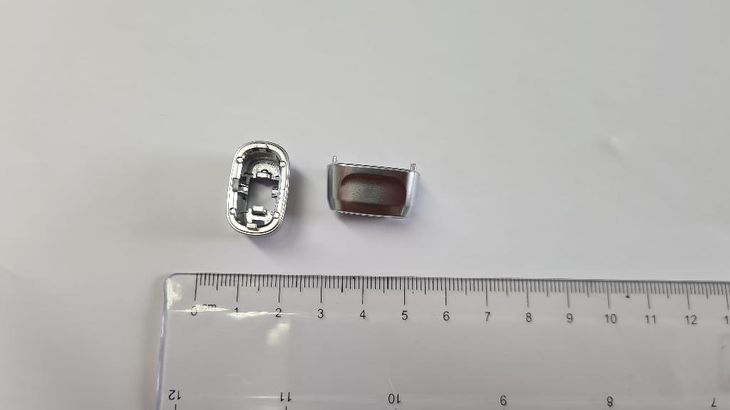 Plastični ročaj pokrovčka ovalne oblike dolžine 23, širine 14 in višine 11 mm.
Uporablja se kot ročaj pokrovčka na sprednji plošči za klimatske naprave na armaturni plošči v avtomobilu.
Narejen je iz akrilonitril-butadien-stirena (ABS) in polikarbonata, prekrit s plastjo bakra (debeline 15 µm), niklja (7 µm) in kroma (0,3 µm). Debelina prevleke je manjša od 49 µm.