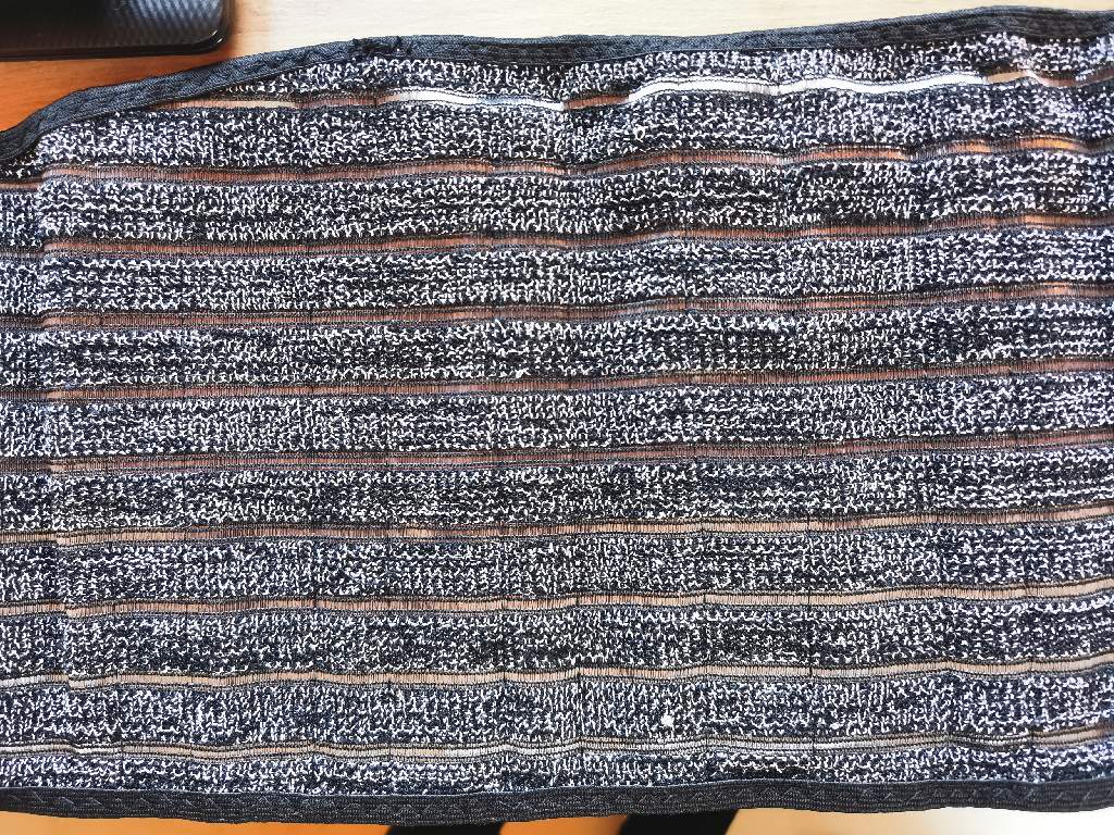 Tekstilni izdelek v obliki podpornega križnega pasu, širinsko raztegljiv, nudi podporo in udobje zaradi svoje elastičnosti. Na hrbtnem delu ima nameščene plastične opornice, ki se lahko odstranijo. Pas se spne s sprimnim trakom, na hrbtnem delu ima prišita dva elastična trakova, ki dodatno pričvrstita izdelek na telo.
Izdelek je namenjen lajšanju bolečin v križnem delu hrbta in nudi oporo trebušnemu delu telesa.
Spleten je predvsem iz sintetičnih vlaken (poliamid, poliester, elastan, bombaž). Vsebuje majhen delež snovi (ogljik), ki ne spadajo v XI. oddelek.  

Pakirano po en kos v kartonsko škatlo.