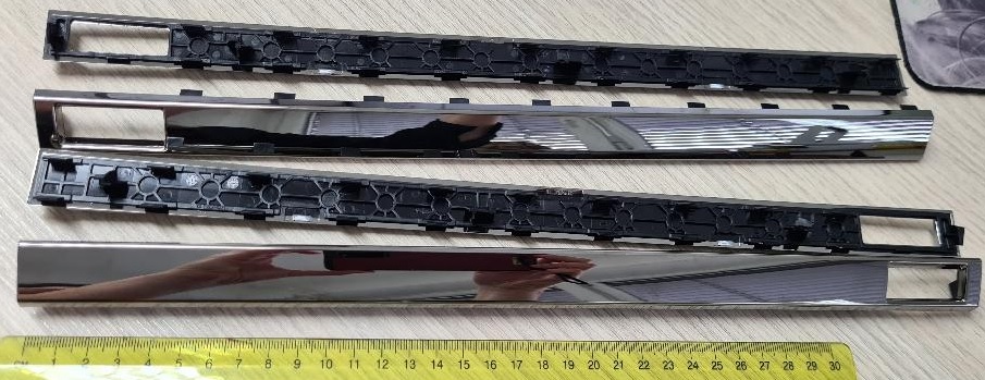 Dekorativni deli podolgovate pravokotne oblike iz plastične mase z dolžino 366.46, višino 16.2 in širino 30.4 mm, imajo na enem koncu odprtino pravokotne oblike z dimenzijami 37 x 15 mm. Deli imajo na eni strani po celotni dolžini več pritrditvenih reber različnih oblik in dimenzij.
Uporabljajo se kot okviri klimatske naprave na sprednjem delu armaturne plošče v avtomobilu.
Izdelani so iz akrilonitril-butadien-stirena (ABS) in polikarbonata, galvansko prevlečeni s sloji bakra (debeline 15 µm), niklja (7 µm) in kroma (0,3 µm).