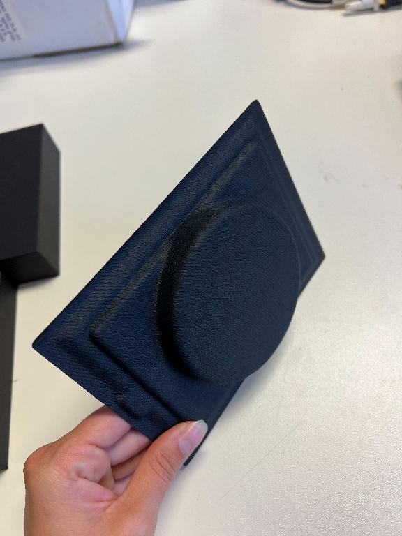 Škatla, črne barve, z dimenzijami 170,8 x 132,3 x 35 mm, sestavljena iz spodnjega dela, pokrova in notranjega vložka. Notranji vložek je posebej oblikovan, da drži izdelek. Na pokrovu je vtisnjen napis.
Uporablja se za pakiranje in zaščito izdelkov podjetja.
Spodnji del in pokrov sta narejena iz kartona, notranji vložek je iz papirne mase.