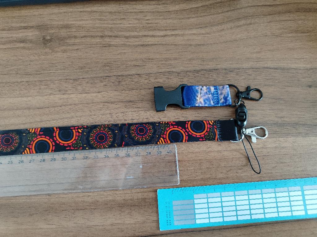 Tovarom je pletený textilný pásik na krk pre deti. Materiál tovaru: polyester, bezpečnostná klapka z plastu, háčik zo základných kovov. Rozmery tovaru: dĺžka 50 cm, šírka 2 cm. Tovar má dva dievčenské a dva chlapčenské dizajny. Tovar sa používa na zavesenie kľúčov alebo preukazu do školy/na autobus pre deti.