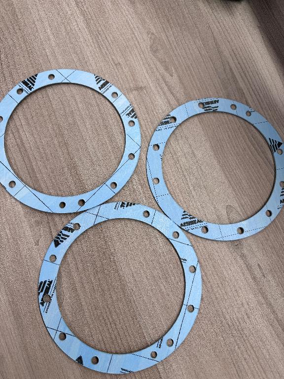 The product is a bespoke gasket for use on pumps/compressors to prevent leakage of fluids or gases.

The gasket size depends on the mechanical seal it is being used on, this can range from ¼” to 6”s in size. They follow a circular shape to bit on a mechanical seal face, but usually will be grooved with holes cut in it, to allow for fitting. The mechanical seal gasket material is generally green in colour
The gasket sheets are usually stacked flat and packed in protective wrapping to prevent damage during transportation. 
Other: Some will be supplied with adhesive backing to allow them to be stuck in place of the seal face.
These mechanical seal gaskets serve to create a seal between two surfaces, preventing the leakage of fluids or gases under various conditions, such as pressure and temperature.
Product is made of aramid fibres, NBR Binder, 

The manufacturing process typically involves mixing the raw materials, including aramid fibres, inorganic fillers, and the NBR binder to form a homogenous blend.
The mixture is then calendared into sheets of the desired thickness. This involves passing the material through rollers to achieve uniform thickness and density.
The sheets are then subjected to a heat treatment process called curing, where the rubber binder is vulcanized, enhancing the material's properties such as elasticity and chemical resistance.
Finally, the cured sheets are cut to the required dimensions and shapes as per specific bespoke gasket designs.
These mechanical seal gaskets are bespoke designed for use only with one of our mechanical seals. All sizing and dimensions will limit them only to be used within one of our seals. The gaskets are ordered to an internally produced technical drawing.