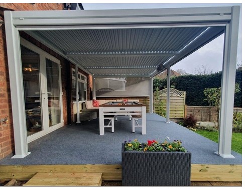 A Garden Room, with an Aluminium frame, louvered roof and side screens,  made from toughened aluminium.
The main frames and roof shutters are made from toughened aluminium with a white powder coating. There are two easy wind mechanisms on the back two corners of the garden room that open and close the roof louvres to allow light and air in as and when required. The louvered roof when closed is completely waterproof but also has drainage channels housed within the shuttered sections which allows excess rainwater to drain off and down specially engineered channels on the inside of the legs and then out through the bottom. The side screens fit into the crossbeam and legs of the main structure as a cassette mechanism. This allows you to pull down the screen to the required length. The side screens are made from Textilene which is made of PVC coated woven polyester non-stretch yarn. Textilene is a contract fabric in terms of durability, specially formulated from yarns developed to withstand wear and tear of outdoor use.
The main structure is shipped unassembled with side panels and side screens and are available in various sizes
