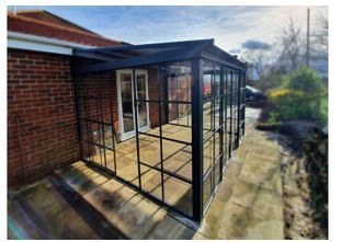 Wall screen house that is a permanent building structure that is imported unassembled, with three sides with an aluminium frame and roof.

The roof system consists of louvered blades which are motorised and can be opened and closed.

There is an in-built guttering system to the building with the water draining out from the corner struts.  Also, there is integral lighting as part of the roof system.  L-shaped brackets are supplied with this building structure, and they can be used to fix the building to a wall using the predrilled holes in the aluminium frames.

The building structure also has four footplates that are fixed to the floor.  This whole unit can be fixed to either hard or soft surfaces that allows it to be a permanent fixture.

Available in various sizes such as 4M X 3M, 5M X 3M and 6M X 4M.
Permanent building structure.  The building can be attached to the residential house.
Aluminium frame and roof.

The roof is polycarbonate, and the side panels are manufactured from tough mica.  The sides of the building are made from 10mm thickness tempered glass and incorporate sliding door panels.

The frame sections are made from steel-reinforced aluminium with dark grey powder coating.  Three glass sides.